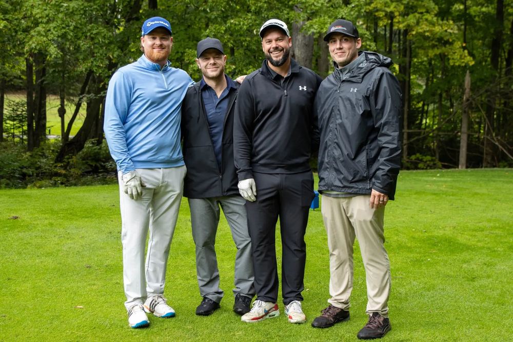 Quatre golfeurs debout sur l'allée, gants aux mains, avant de s'élancer